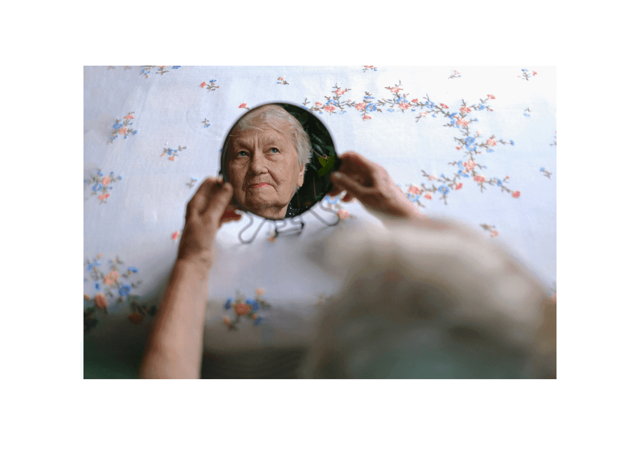 elderly woman looking in the mirror deciding between a assisted living or nursing home