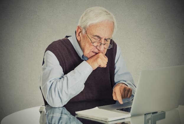 Elderly man at laptop preparing for death with end-of-life planning