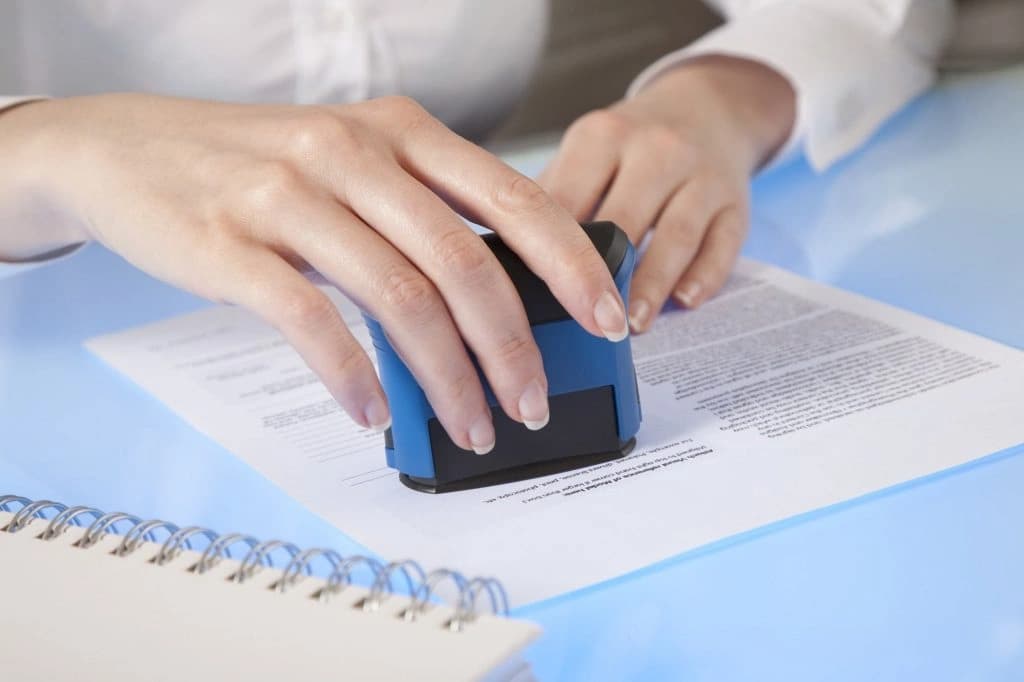 Do Wills Need to Be Notarized – Understanding Legal Requirements Person notarizing a legal document with a stamp, illustrating the question: Do wills need to be notarized?