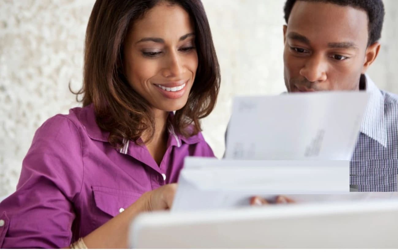 Couple finding out they are a beneficiary in a will Couple reading estate documents after learning they are beneficiaries of a will