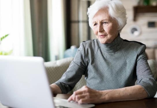 Woman looking to search obituary free (1) Woman using a computer to perform an obituary search free online.
